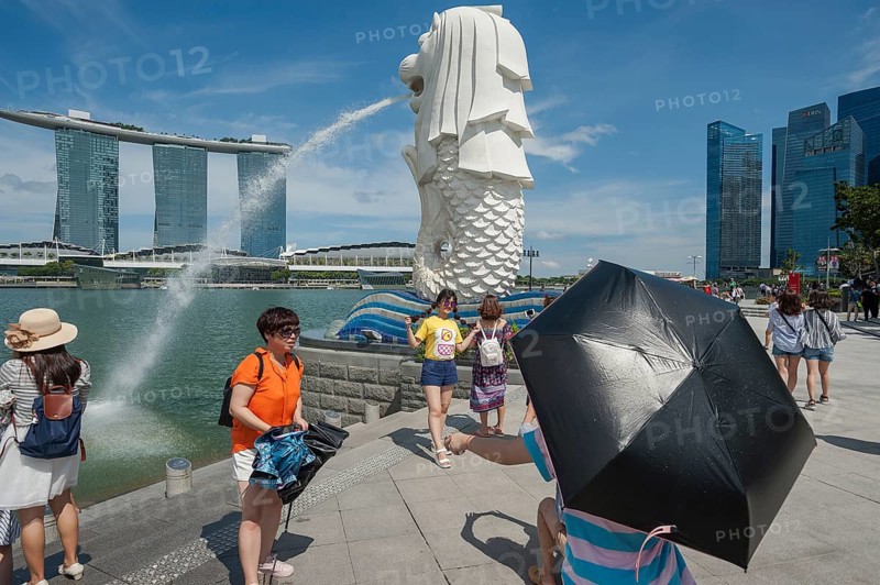 20.08.2016, Singapore, Republic of Singapore, Asia, Tourists visit the Merlion Park with the figure of the Merlion along the Singapore River in Marina Bay. The Merlion is a mythical creature and is half lion and half fish and at the same time Singapore's landmark and mascot. In the background is the striking Marina Bay Sands Hotel with its three towers