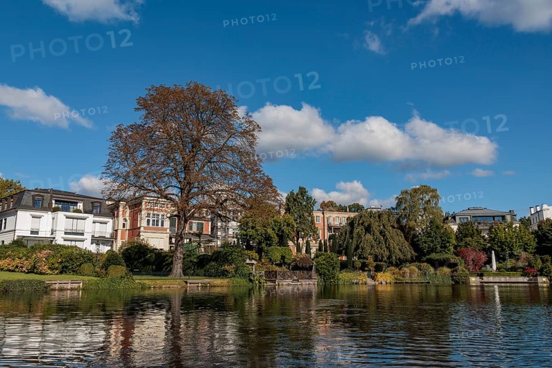 Stylish townhouses reflected in the water, surrounded by lush autumn foliage, Alster, Hamburg, Germany