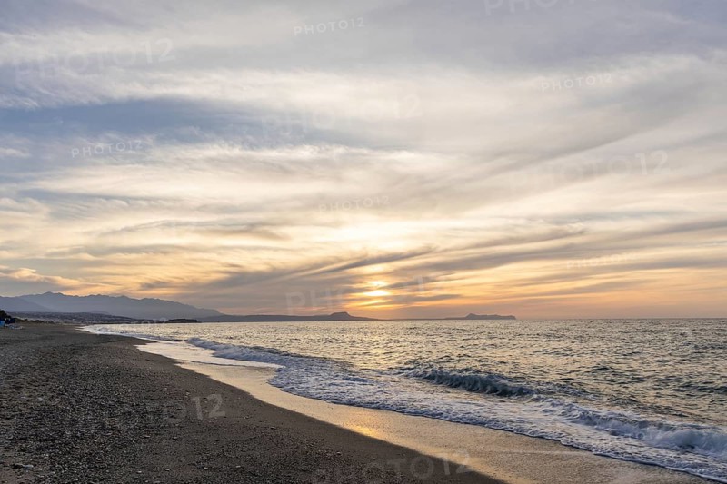 Beautiful coastline with a sandy beach and pebble beach at sunset. Beautiful sky colouring in the tourist and hotel area Platanes Beach, Rethymno, Crete, Greece
