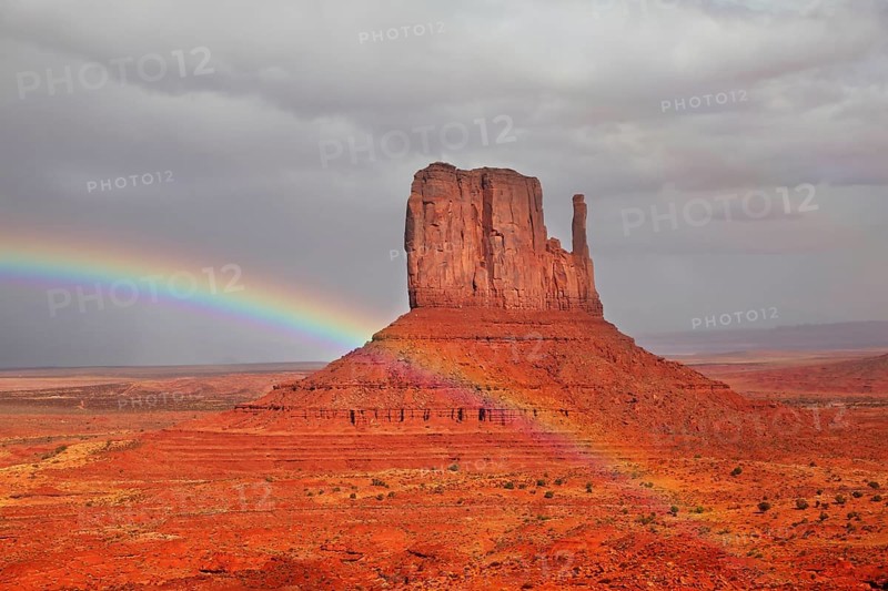 Red Desert. Monument Valley - Navajo Reservation during the summer thunderstorms. The magnificent rainbow over the famous red sandstone Mittens