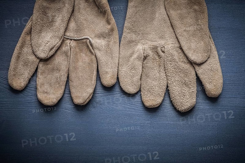 Pair of protective working gloves on wooden board
