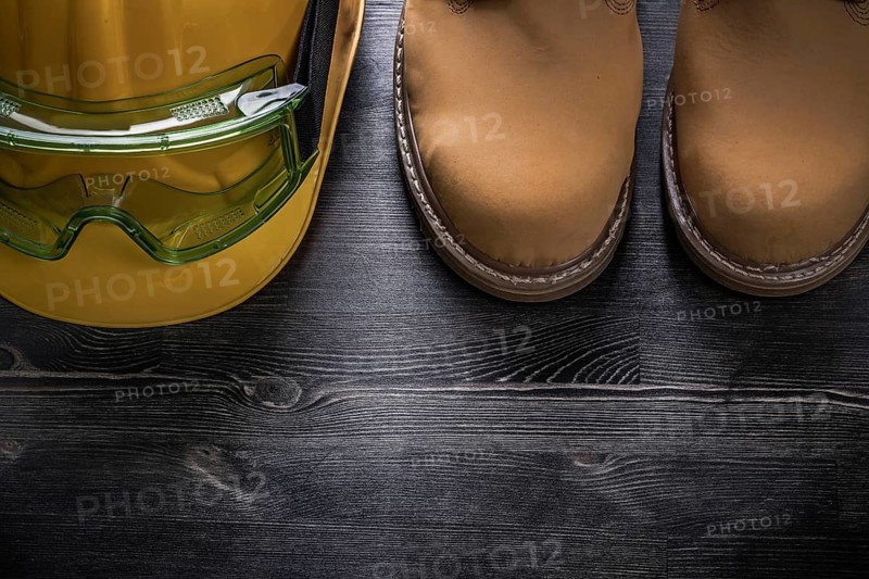 Protective goggles hard hat safety boots on wood board