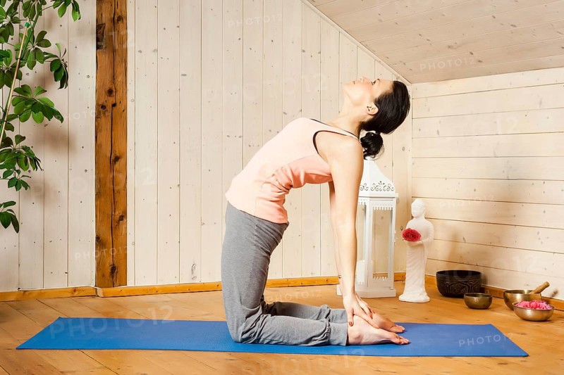 An image of a pretty woman doing yoga at home - Ushtrasana