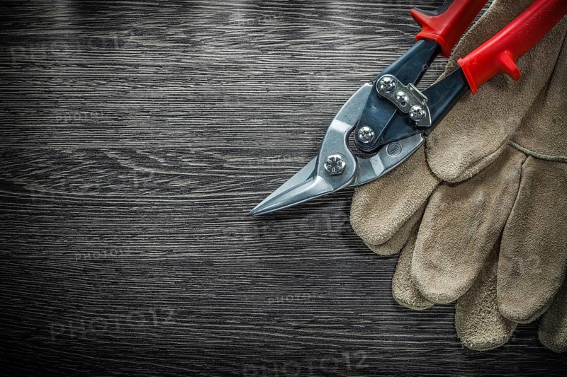 Pair of protective gloves steel cutter on wooden board