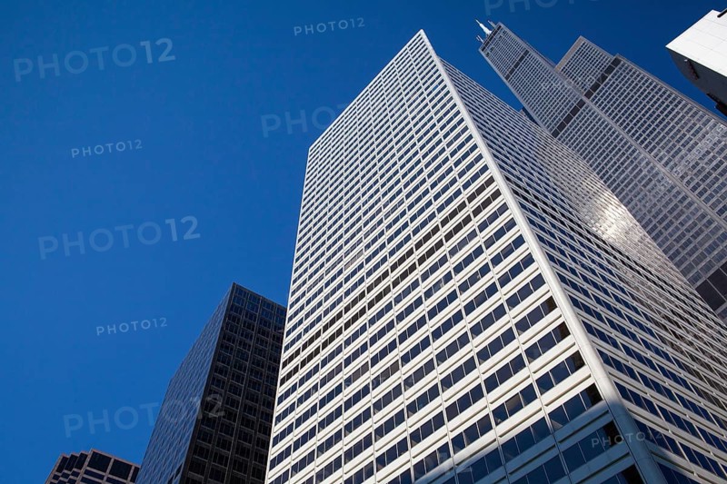Looking up at business building in downtown, Chicago, USA. A view up through tall skyscrapers to a patch of blue sky