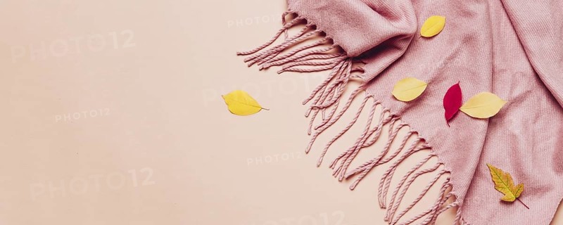 Pink cozy scarf with tassels and scattered leaves on pastel banner