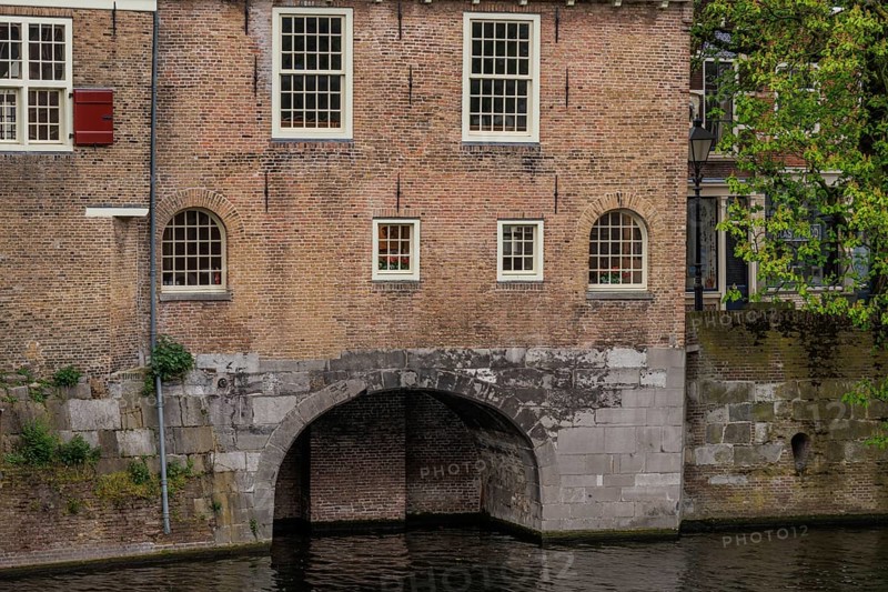 Brick wall with several windows and a large arch leading into the water, Rotterdam, Netherlands