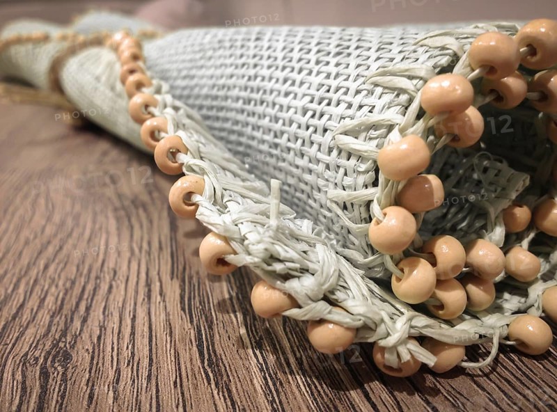 Small roller wicker mat on vintage table. Furnishing accessory for home. Close-up