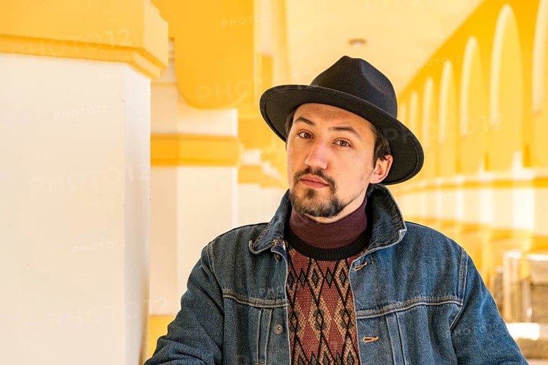 Portrait of a stylish handsome young man with a scarf outdoors. A serious man wearing a hat and a jaket looking confident at the camera