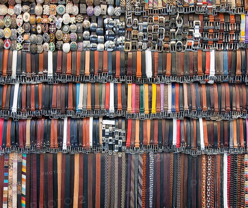 Many colored leather belts on a market