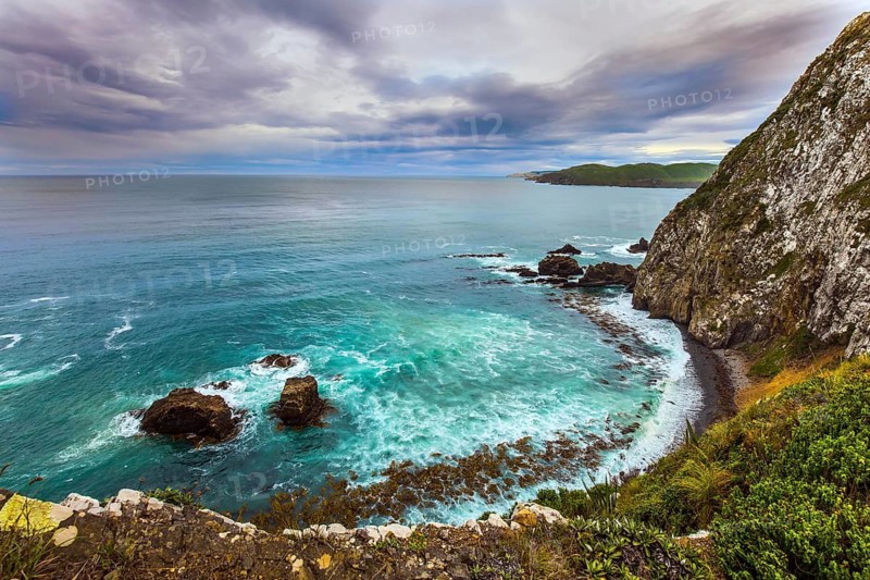New Zealand. The picturesque coast of the Pacific Ocean near Nugget Points. Sunset sky portends a storm. Big stones along the shore. The concept of active, environmental and photo tourism