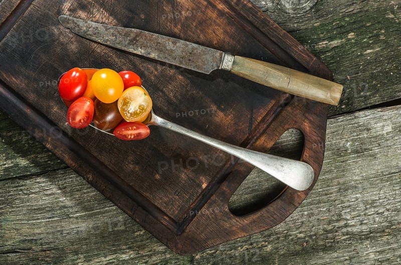 Variety of cherry tomatoes in spoon on wood