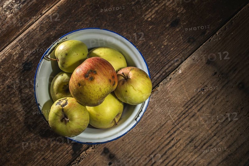 Apples in vintage metal cup on white wooden table