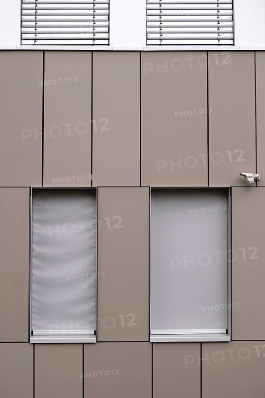 A modern office building façade with sheet metal cladding and an installed surveillance camera