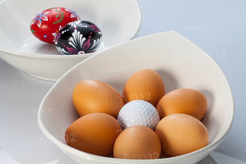 Two white ceramics bowls, easter eggs and golf balls