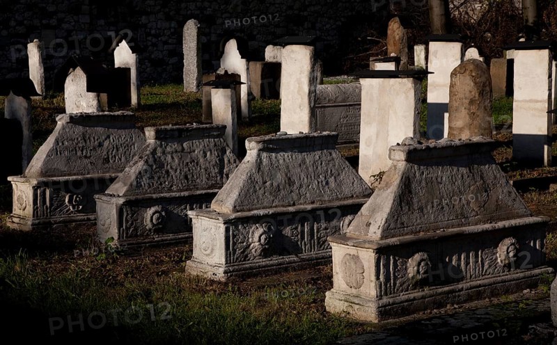 Lined up sarcophagi, tombstones behind them