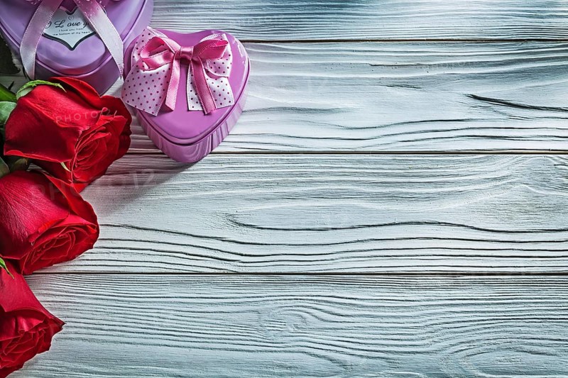 Set of metal heart-shaped present boxes red roses on wooden board celebrations concept