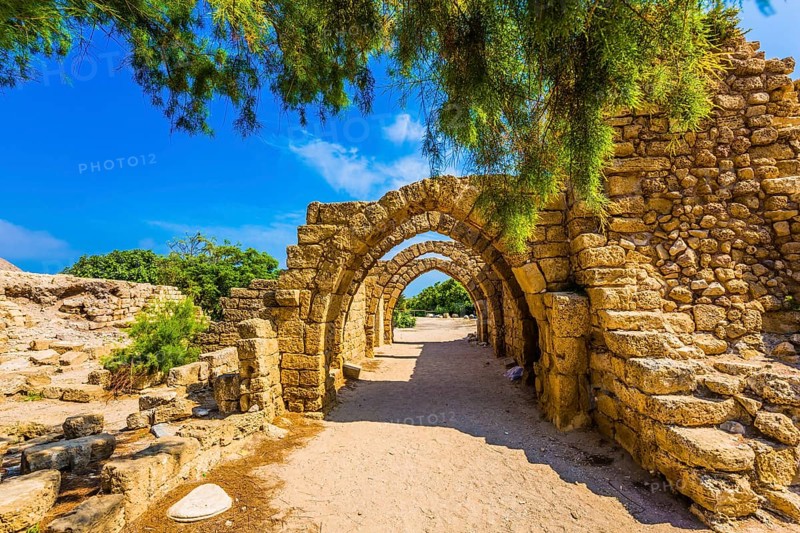 Sunny spring day. Arched passage - covered street. Picturesque ruins of the ancient seaport Caesarea. Israel. Concept of ecological and historical tourism