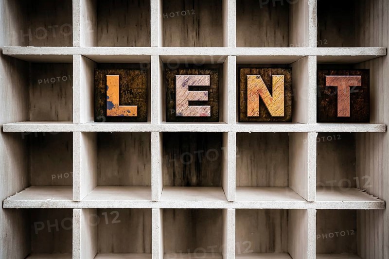 The word LENT written in vintage ink stained wooden letterpress type in a partitioned printer's drawer