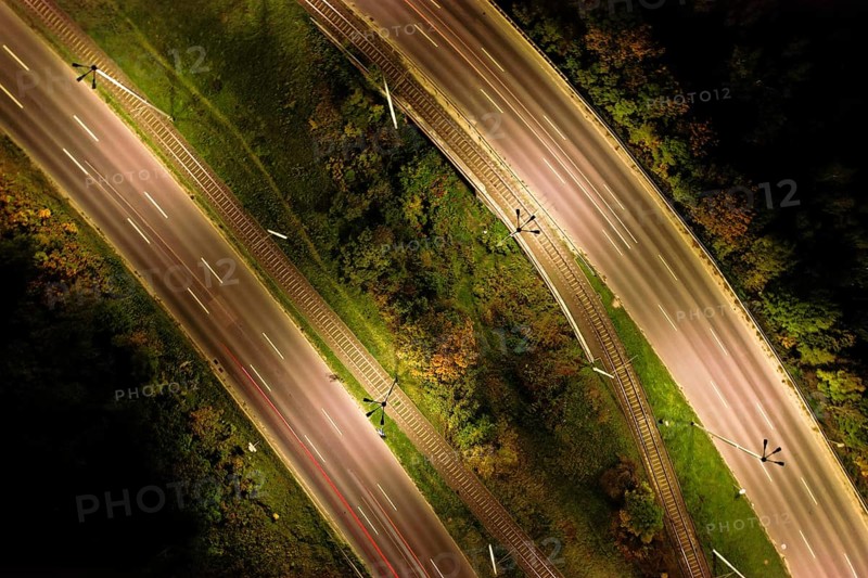 Top down view to road. Romantic night aerial photo of cars traveling. The light on the road at night in city. Background scenic road drone view. Tram railways background