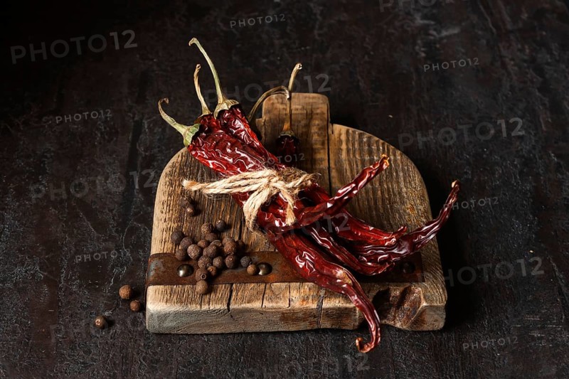 Dried chili peppers on a wooden board, dark photo