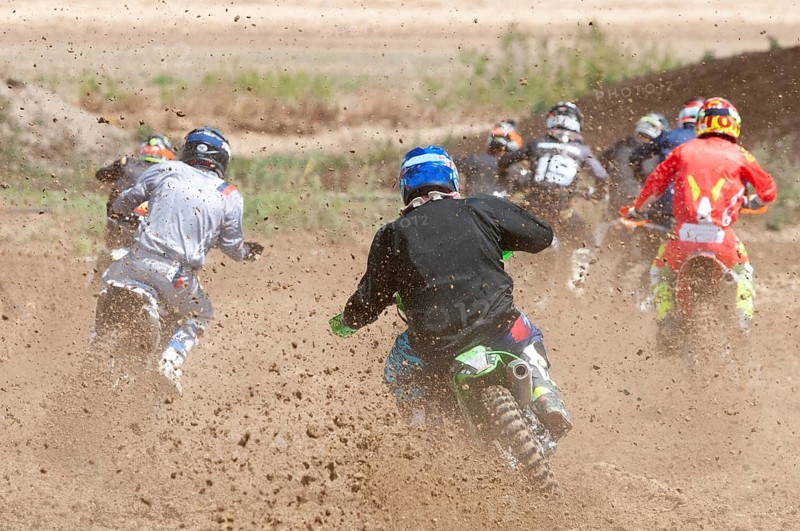 Unrecognized athletes riding a sports motorbike racing fast on a motocross track field. Challenge and competition
