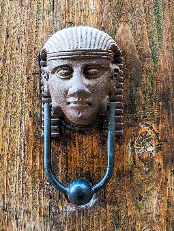 Vintage style doorknocker of an Egyptian head, a door in Italy