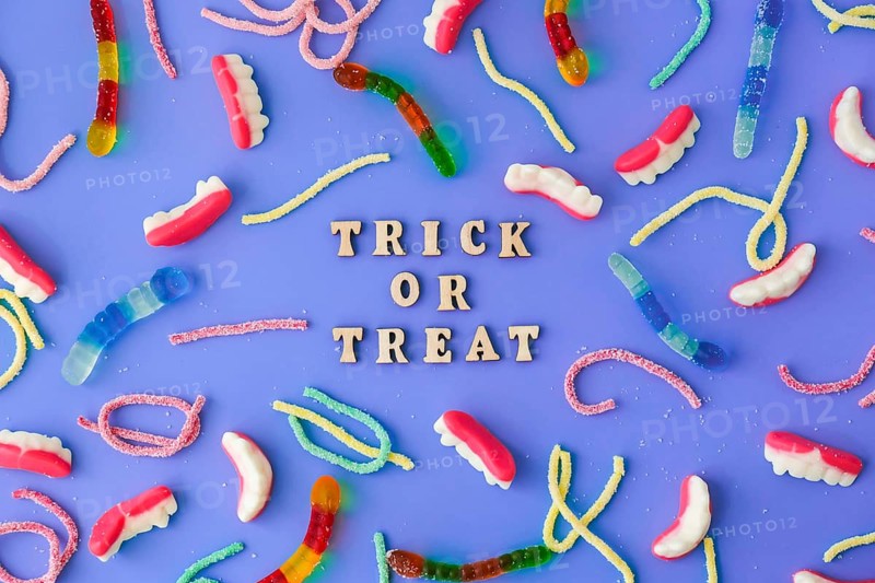 Halloween concept. Halloween party decorations with words TRICK OR TREAT, sweets, top view flat lay on blue background. Greeting card