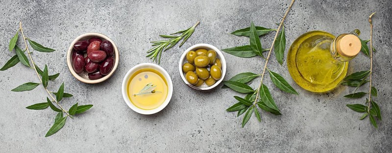 Composition with green and brown olives, extra virgin olive oil in glass bottle, olive tree branches on gray concrete stone rustic background overhead, Mediterranean concept, food photography, food photography
