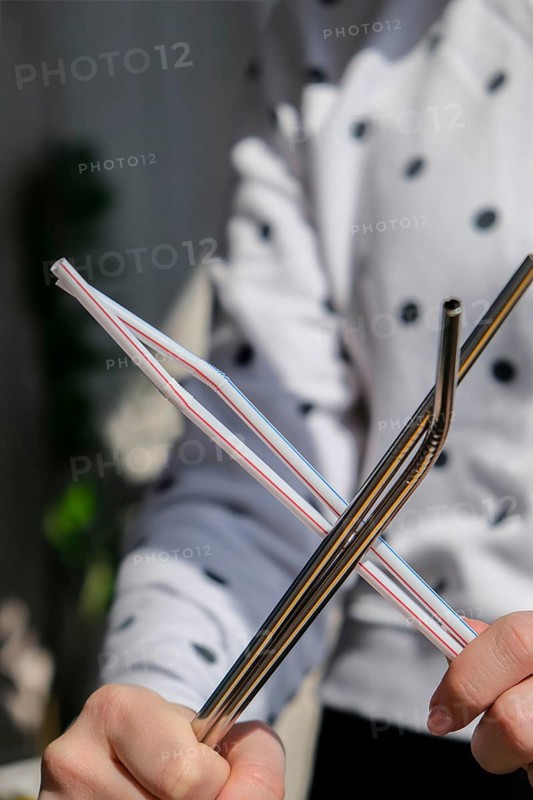 Woman holding Reusable Metal and plastic drinking Straws. Female Hand on reusable collapsible drinking straw. Eco lifestyle and zero waste concept. Plastic free. Stainless metal straws