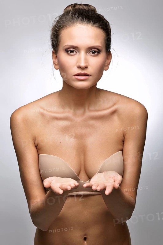 Beautiful woman in flesh color underwear showing by hand. Studio shooting