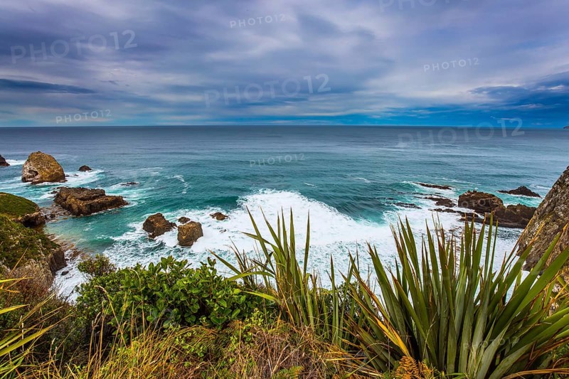 Foamy ocean surf before the storm. South Island, New Zealand. The picturesque coast of the Pacific Ocean near Cape Nugget. The concept of active, environmental and photo tourism