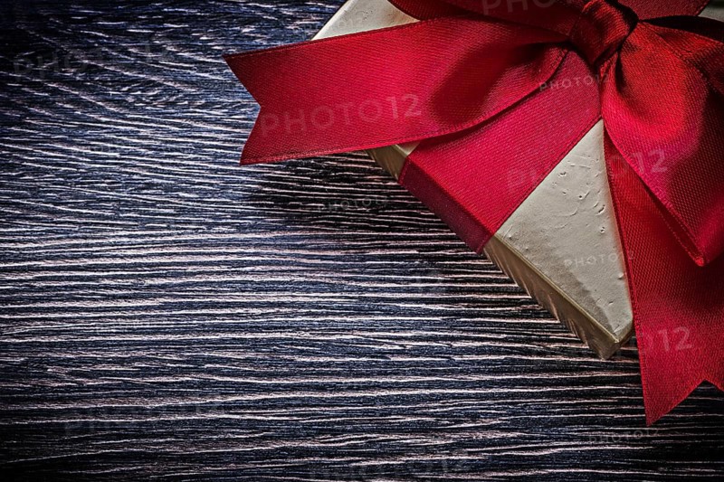 Tied wrapped gift box on wooden board holiday concept