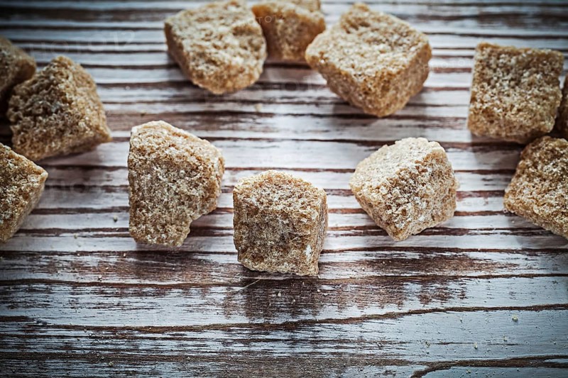 Vintage cane sugar cubes on wooden board top view
