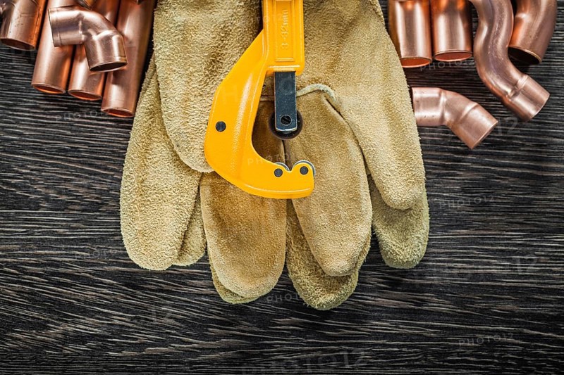 Plumbing copper water pipe scissors leather safety gloves on wooden board