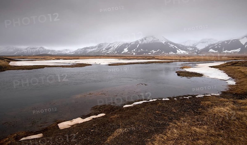 Typical Icelandic dramatic landscape with frozen lake and mountains covered in snow in Iceland