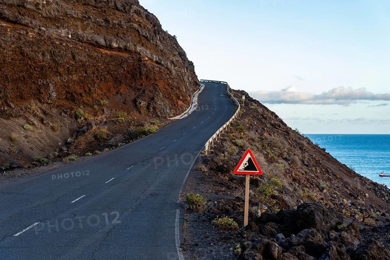 Empty road with risk of landslide traffic sign in a volcanic landscape in the Island of La Palma, one of the Canary Islands, in the Cumbre Vieja volcano area near Teneguia volcano