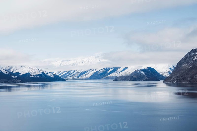 Fascinating view of a wide lake with snow-capped mountains under a blue sky, Wanaka, New Zealand