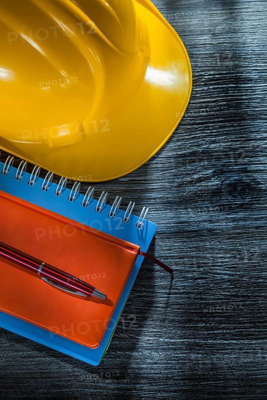 New notebooks pen safety building helmet on wooden board