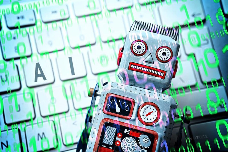 Robot on computer keyboard, symbolic photo of artificial intelligence, photomontage