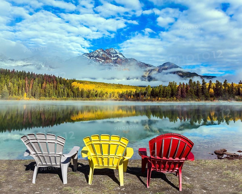 Rocky Mountains of Canada. Three comfortable multi-colored deck chairs stand by the Piramid lake. Concept of ecological, active and photo-tourism