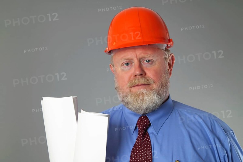 Man in suit with construction helmet on grey background