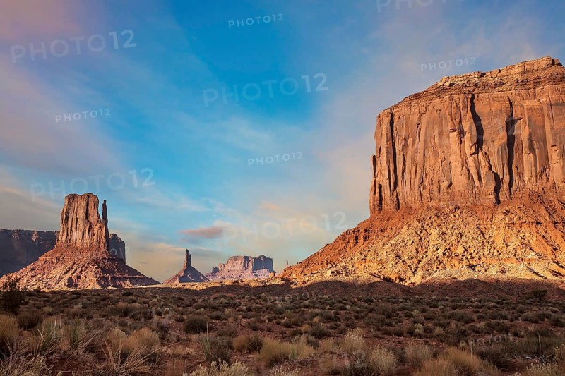 The famous cliffs Mittens in Monument Valley. The rocks - outcrops made of red sandstone. Bright multi-color sunset on the red stone valley. The concept of active, environmental and photo tourism