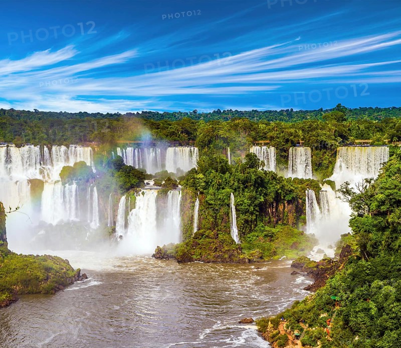 Several waterfalls from Iguazu Falls. Powerful two-stage waterfall creates rainbow and watery dust. The concept of exotic and extreme tourism