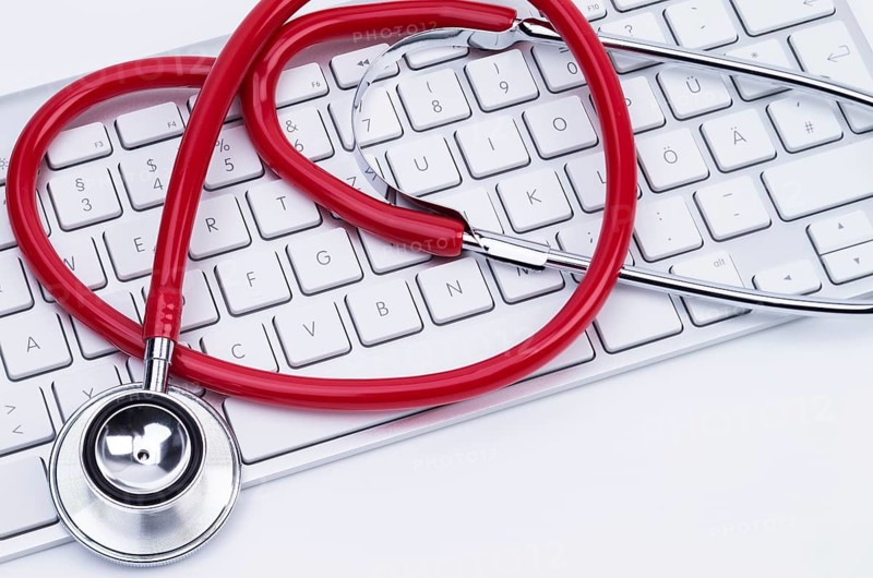 Image shows a red stethoscope at a computer keyboard