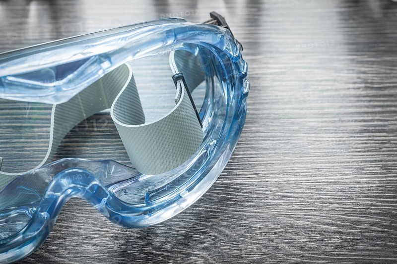 Safety plastic glasses on wooden board
