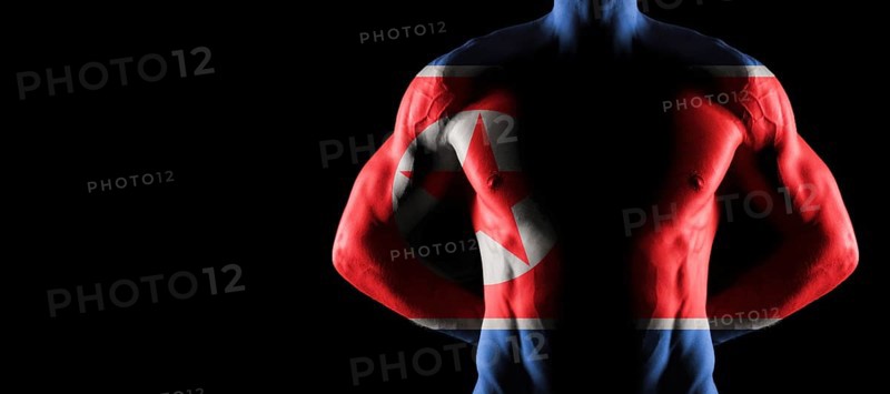 North Korea flag on muscled male torso with abs, black background