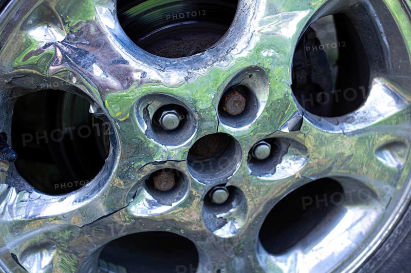 Cracked chrome wheel rim showing rust detail around bolt area
