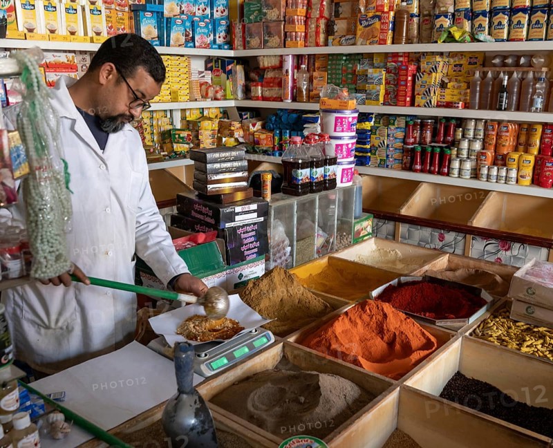 Er-Rich, Morocco, 7 March, 2024: Moroccan shopkeeper mixing spices in his shop in the market of Er-Rich