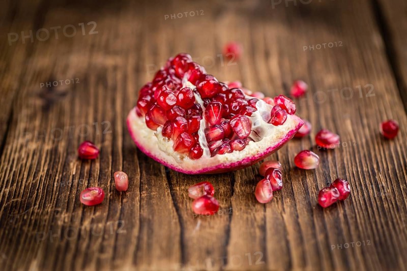 Pomegranate on an old wooden table as detailed close-up shot (selective focus)